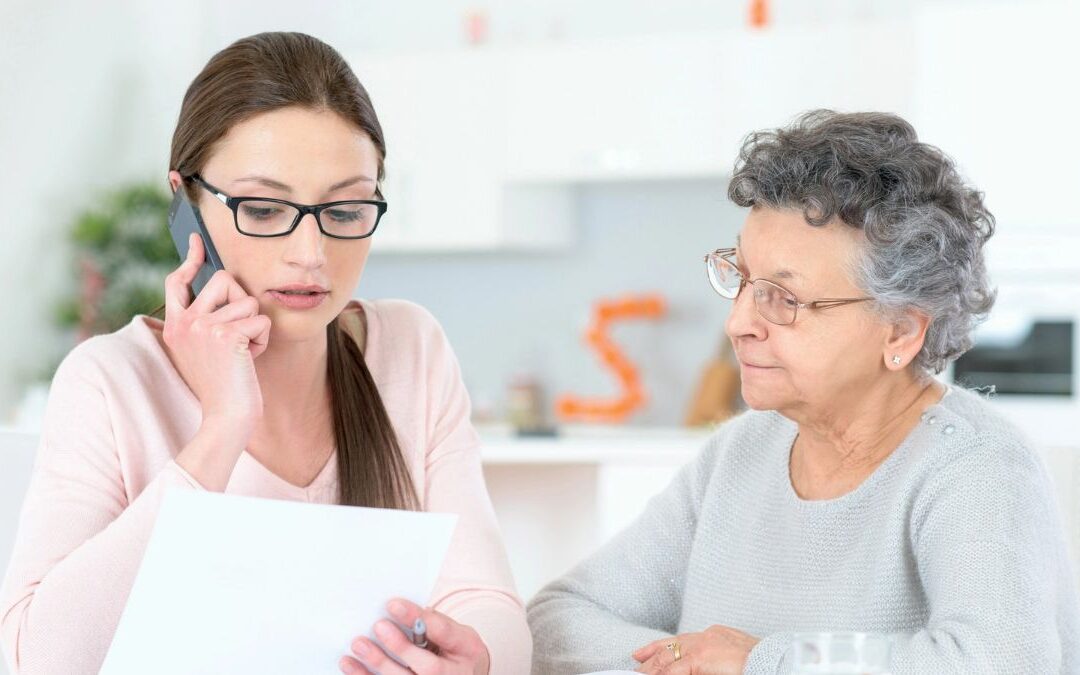 Adult daughter helping her elderly mother arrange an appointment at home