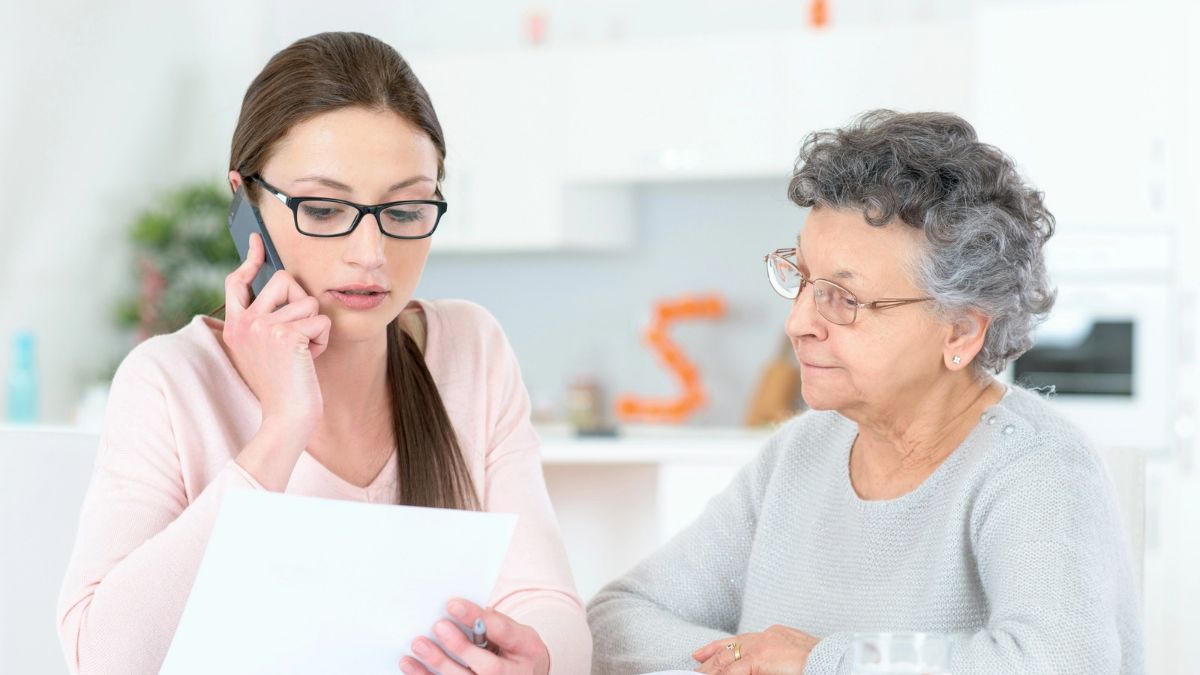 Adult daughter helping her elderly mother arrange an appointment at home